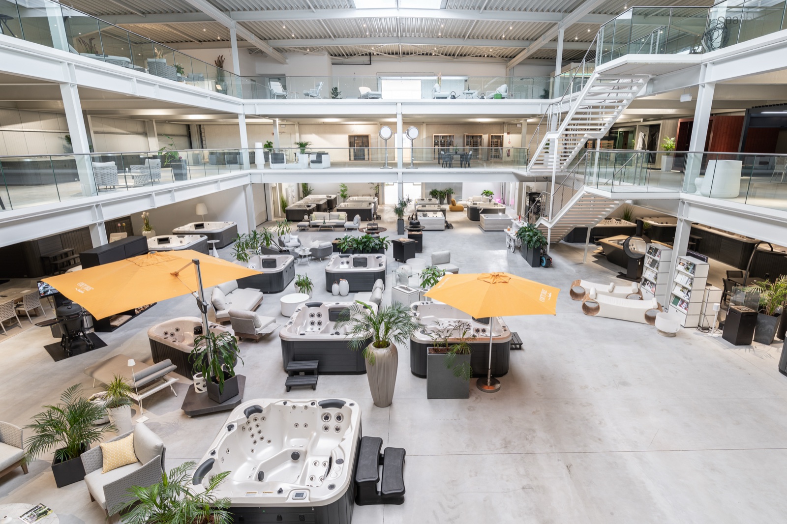 SPA Deluxe Showroom: zweistöckige Halle mit zahlreichen Whirlpools, Lounge-Möbeln und Sonnenschirmen zum Probesitzen